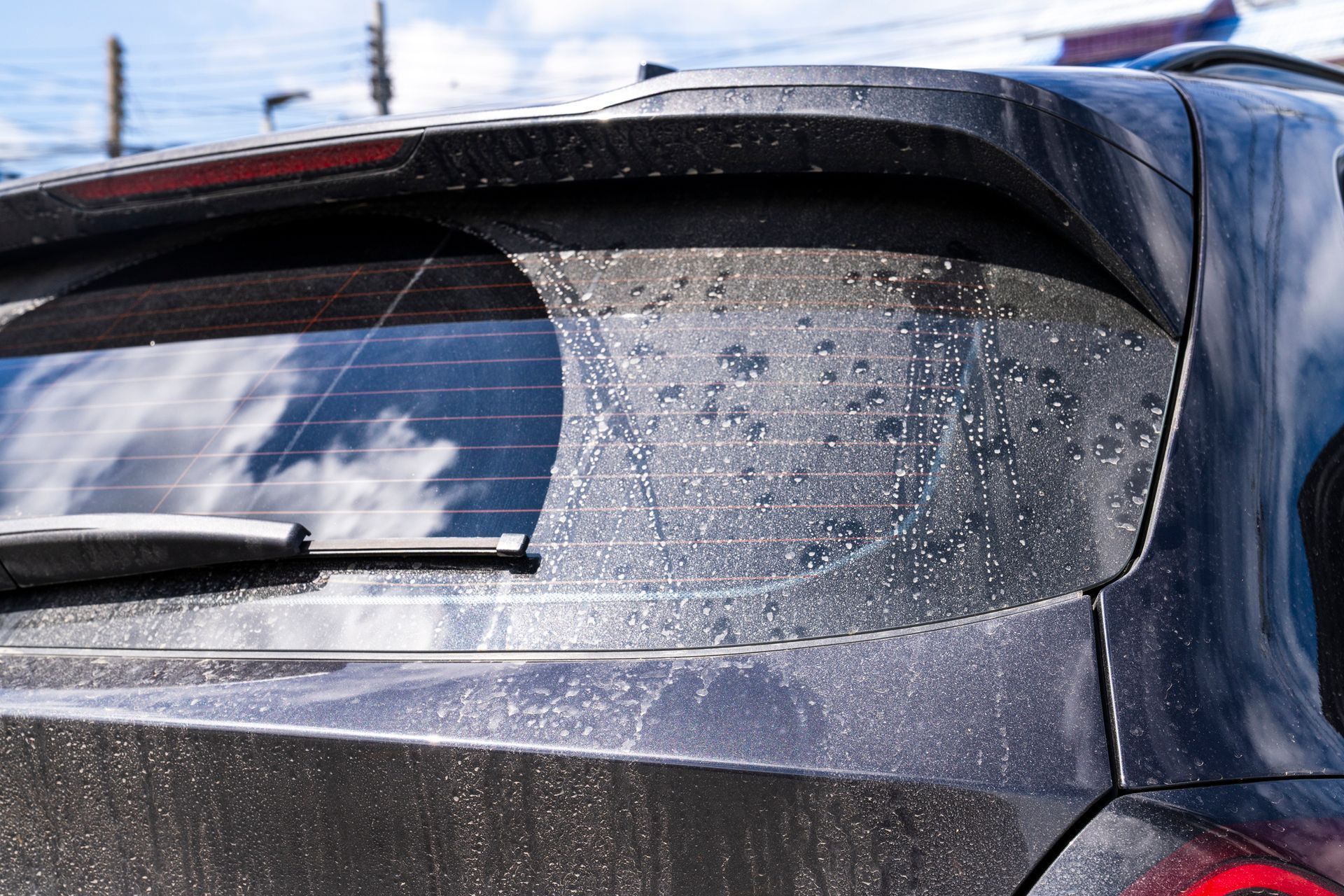 A close up of a dirty car with water drops on the windshield.