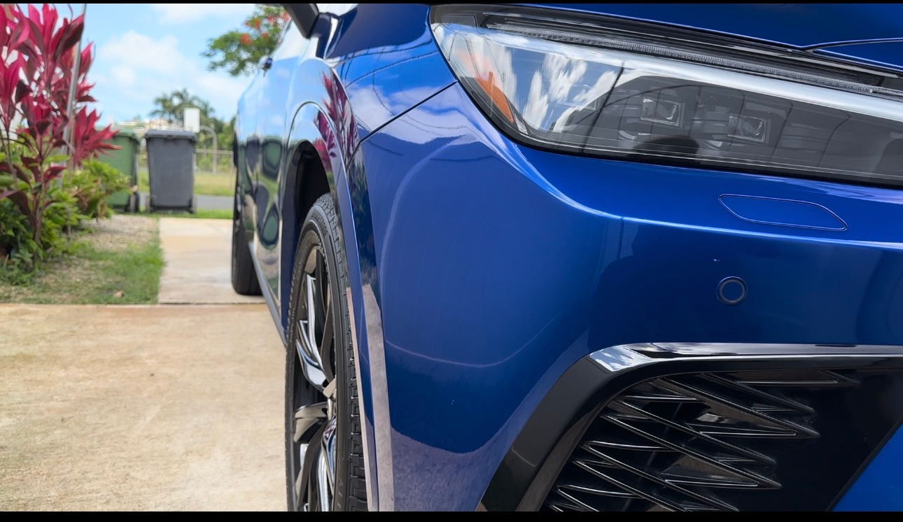 A close up of a blue car parked in a driveway.