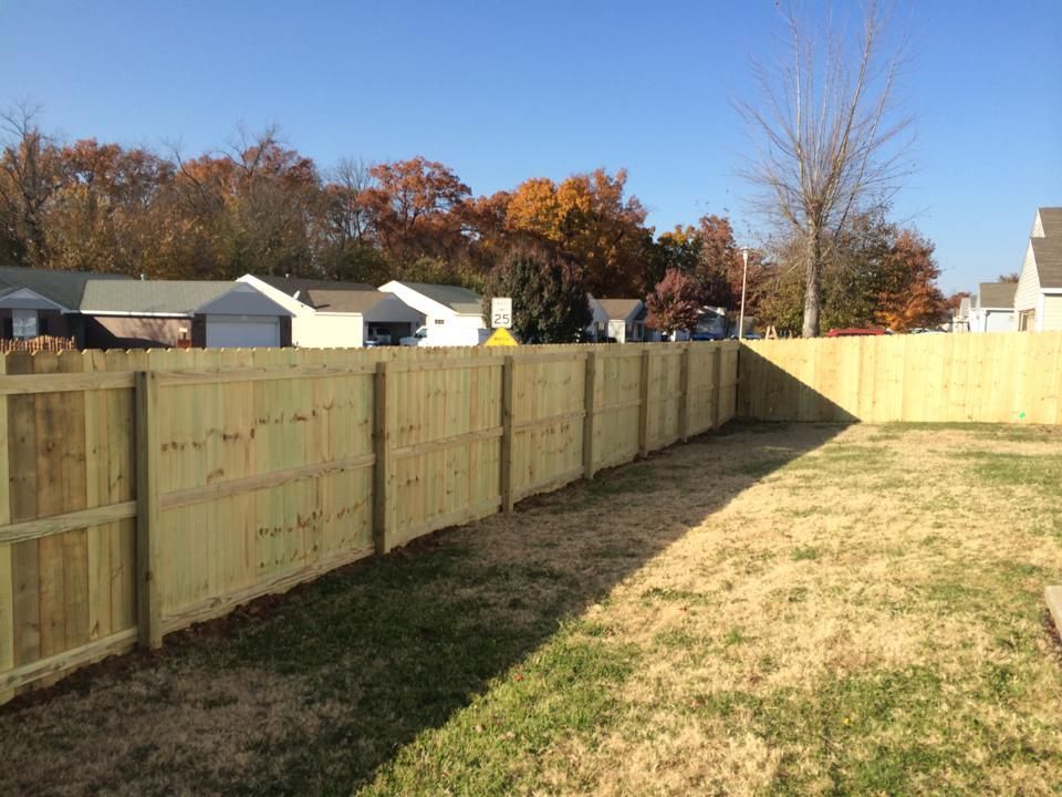 A wooden fence is in the backyard of a house.