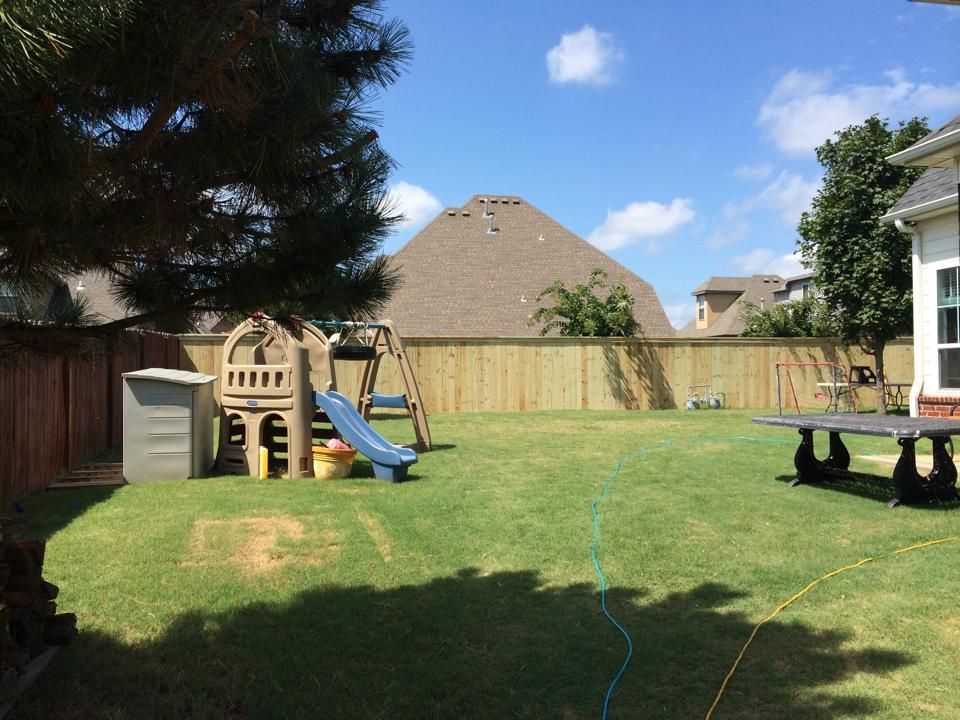 A backyard with a playground and a wooden fence