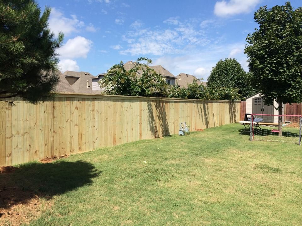 A wooden fence surrounds a lush green yard.