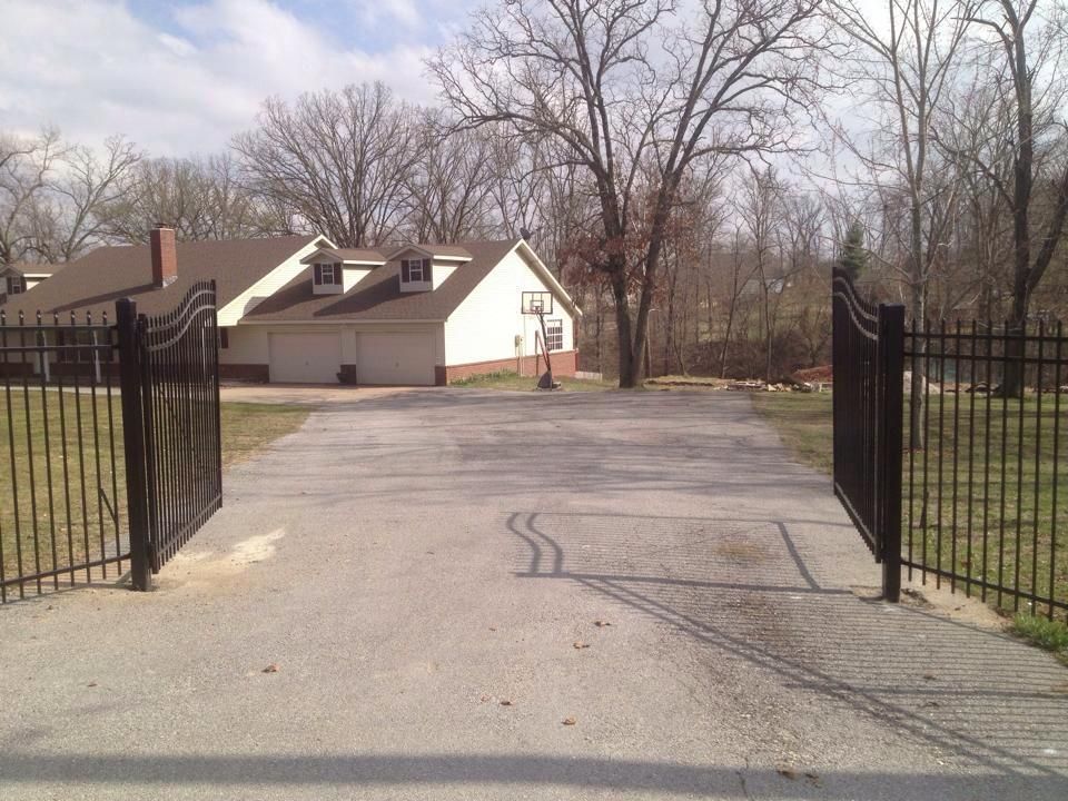 A driveway with a fence and a house in the background