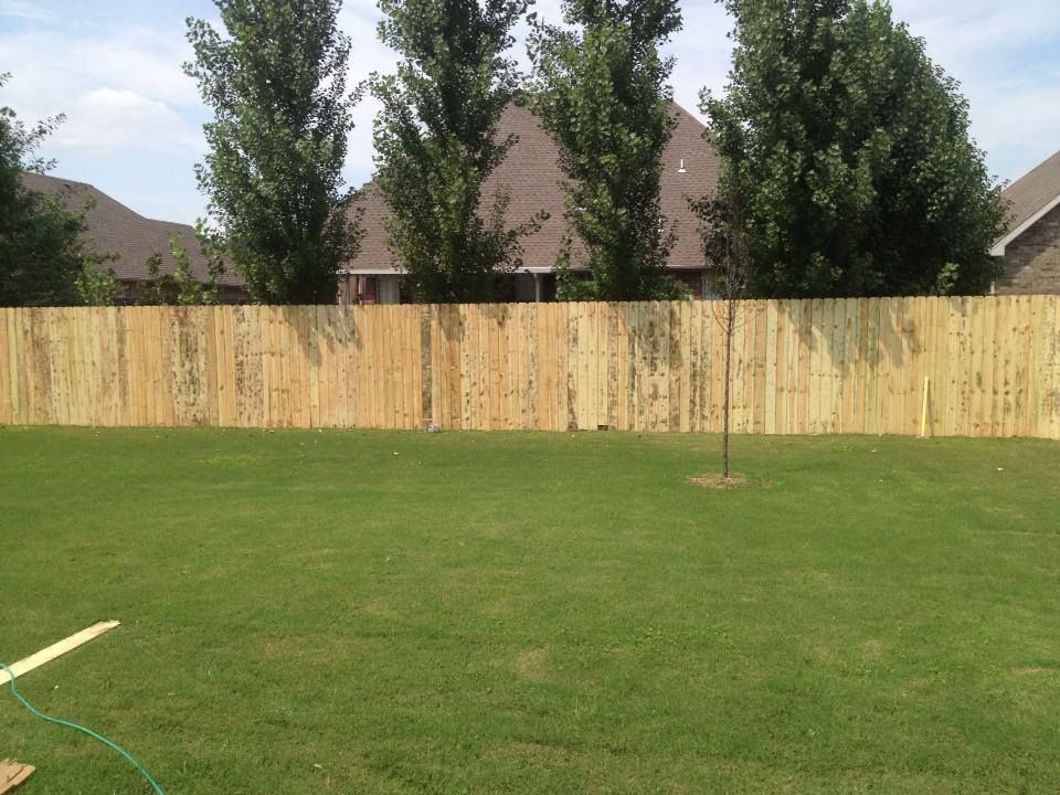 A wooden fence surrounds a lush green yard
