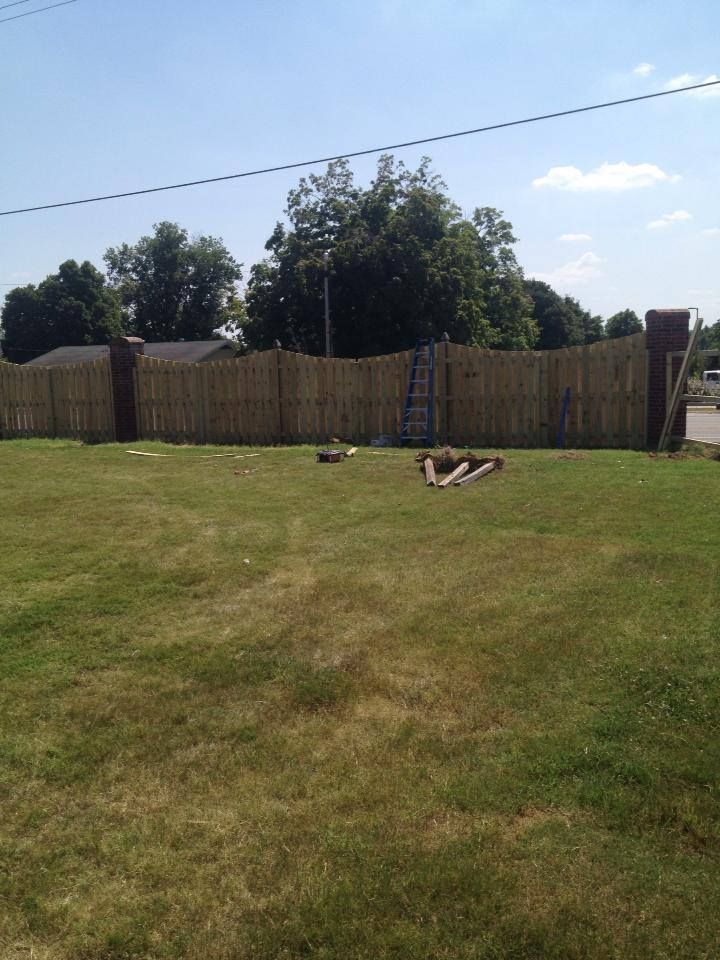 A wooden fence surrounds a lush green field