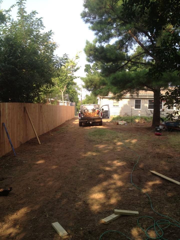 A wooden fence is being built in the backyard of a house.