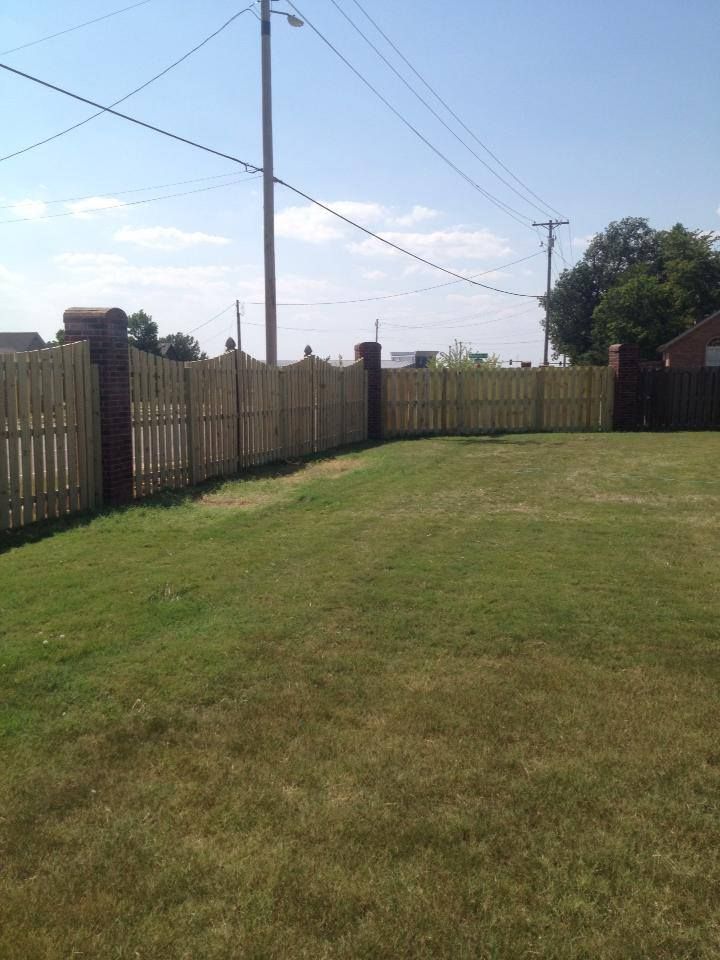 A wooden fence surrounds a lush green field