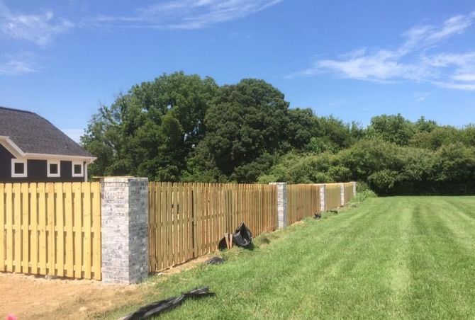 A wooden fence is sitting in the middle of a lush green field.