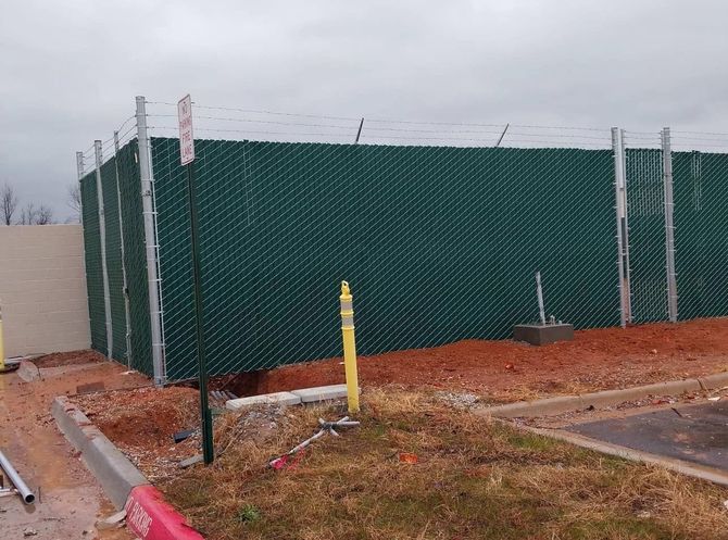 A green chain link fence is surrounding a building under construction.