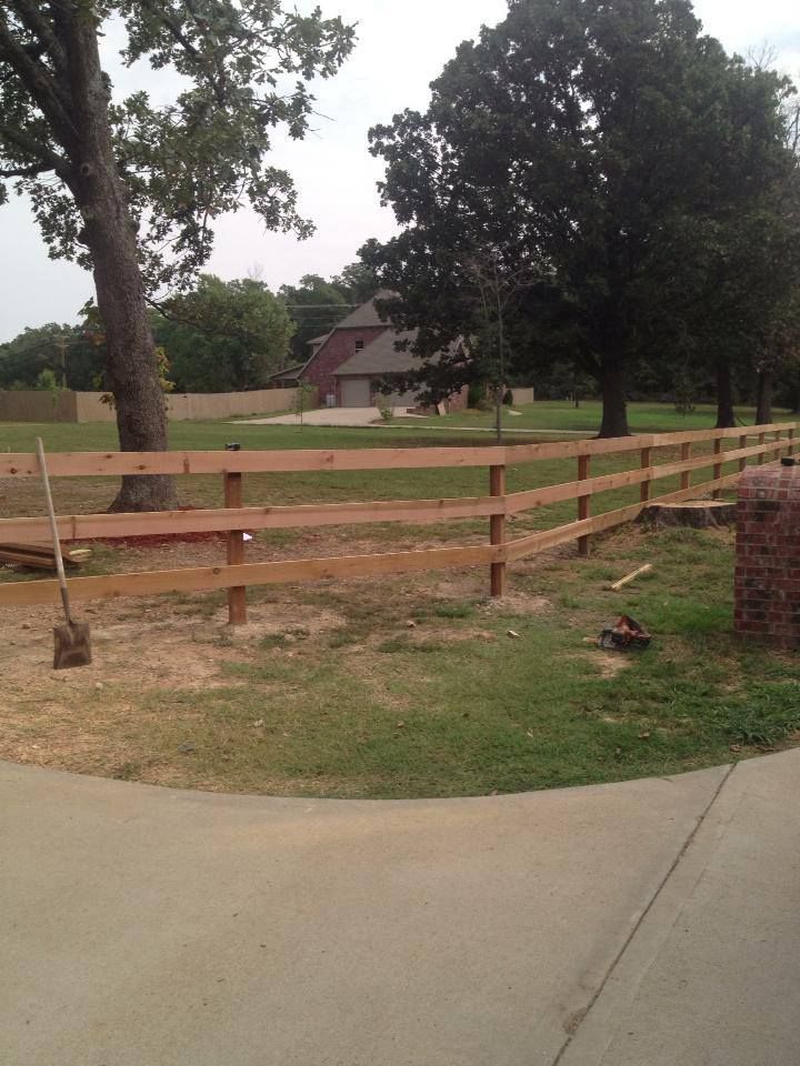 A wooden fence is in the middle of a grassy field.