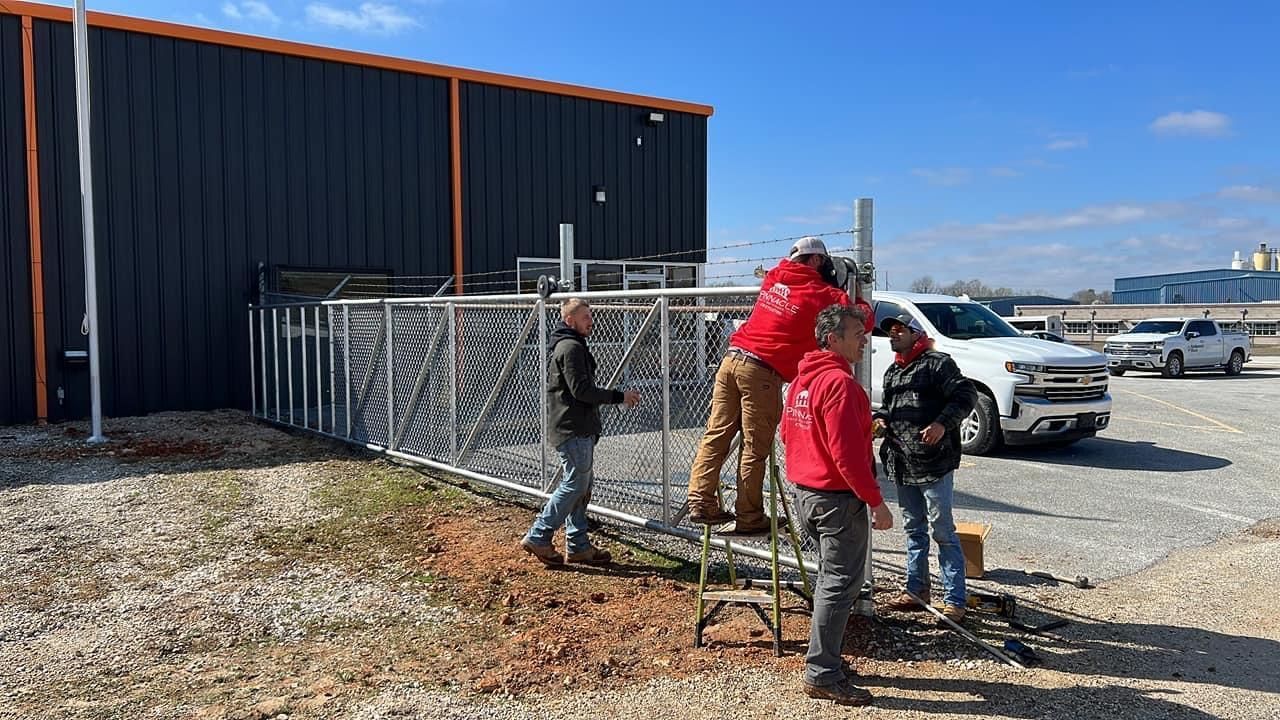 A group of people are working on a fence in front of a building.