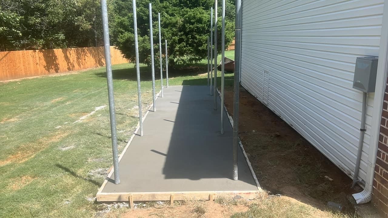 A concrete walkway is being built in the backyard of a house.