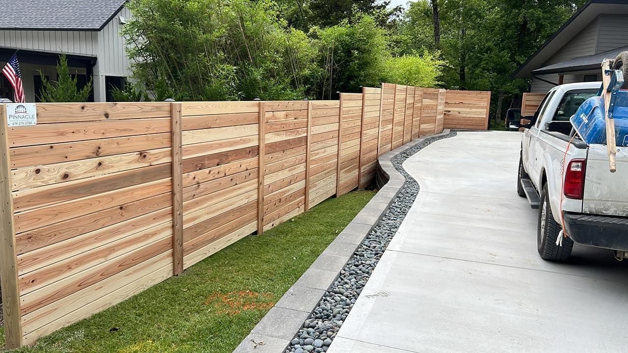 A white truck is parked in front of a wooden fence.