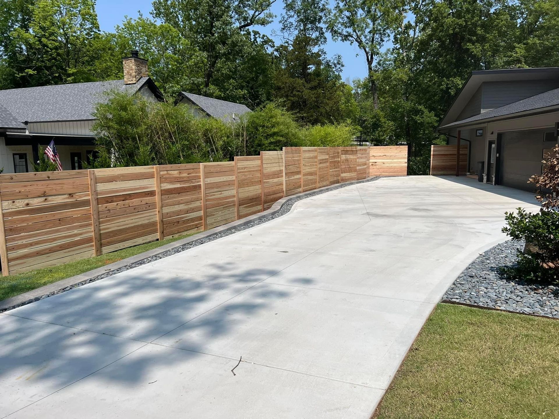 A driveway leading to a house with a wooden fence