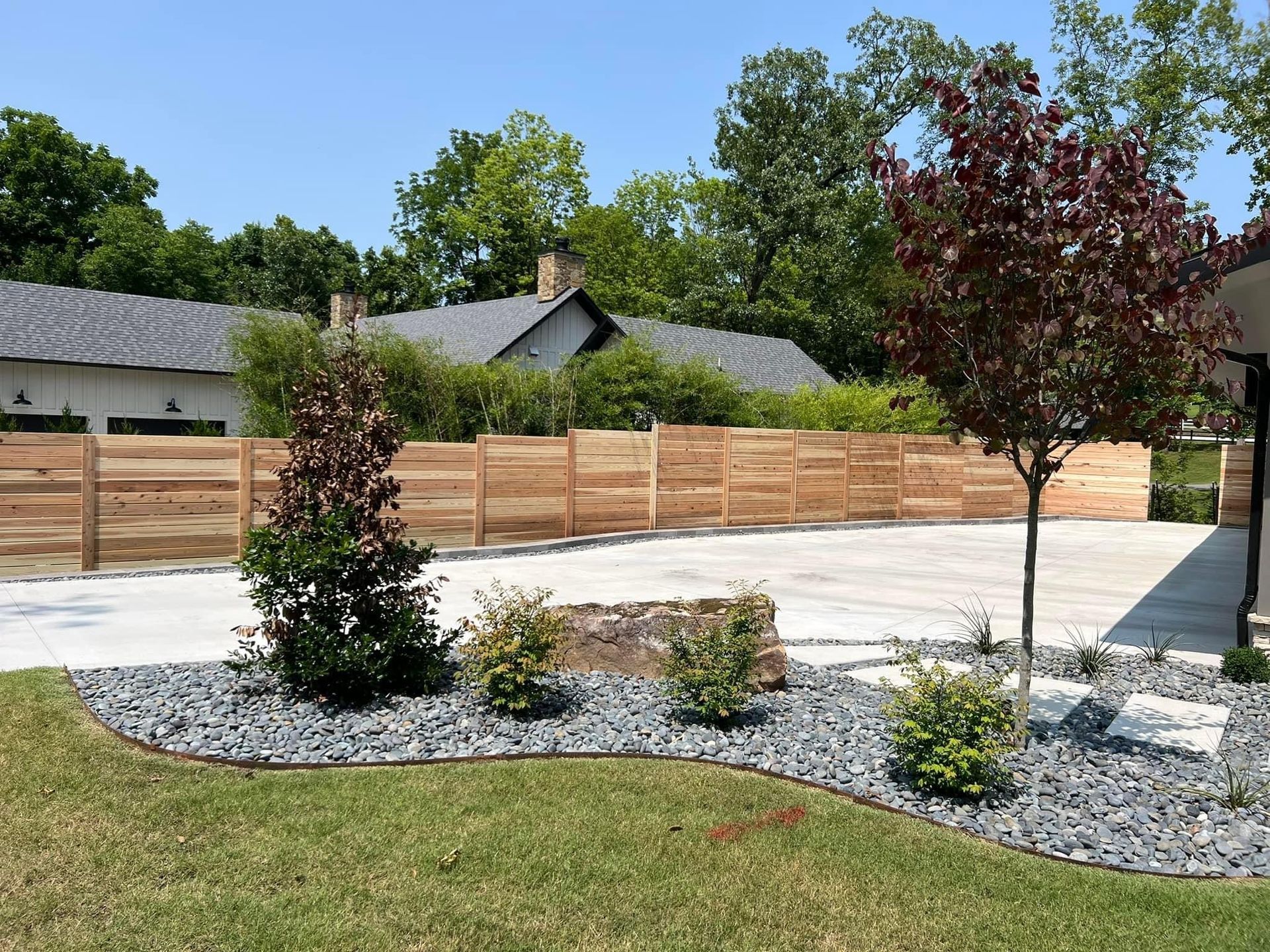 A wooden fence surrounds a driveway in front of a house.