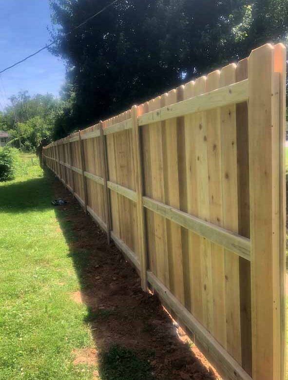 A wooden fence is sitting in the middle of a lush green field.