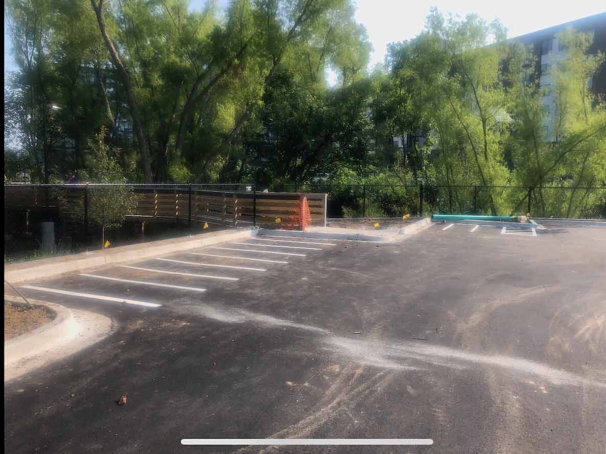 A parking lot with a fence and trees in the background