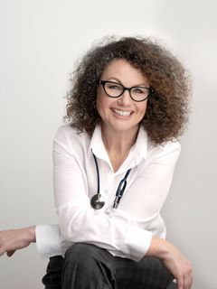 The woman is wearing glasses and a stethoscope around her neck.