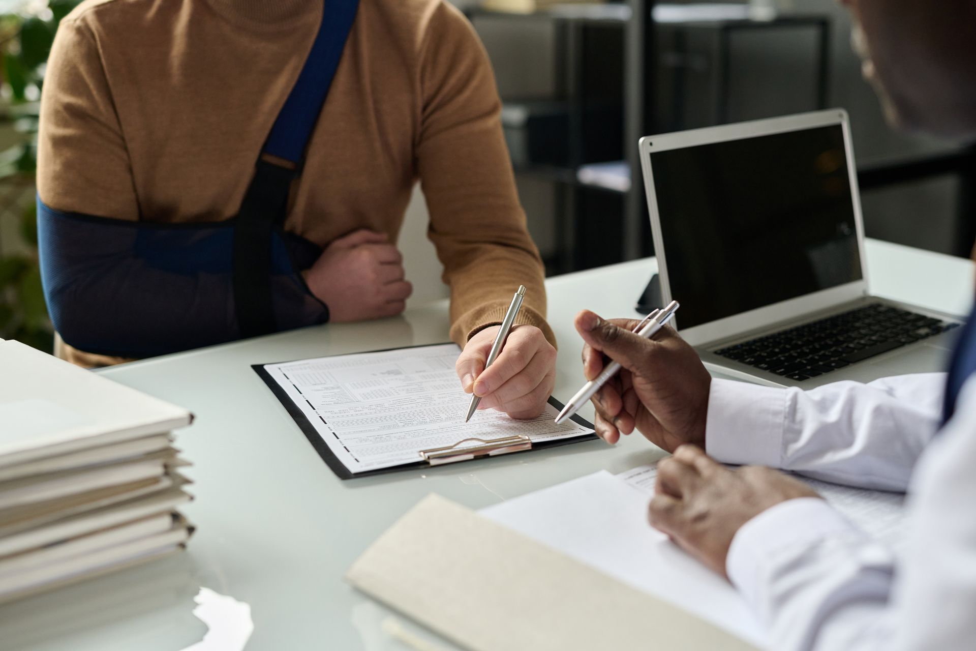 A man with a broken arm is sitting at a table with a doctor.