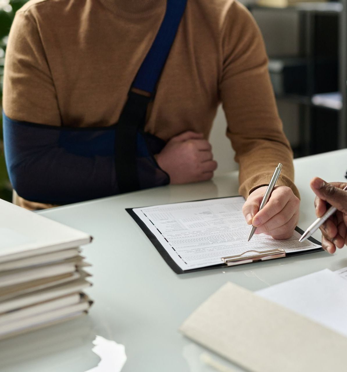 A man with a broken arm is writing on a clipboard