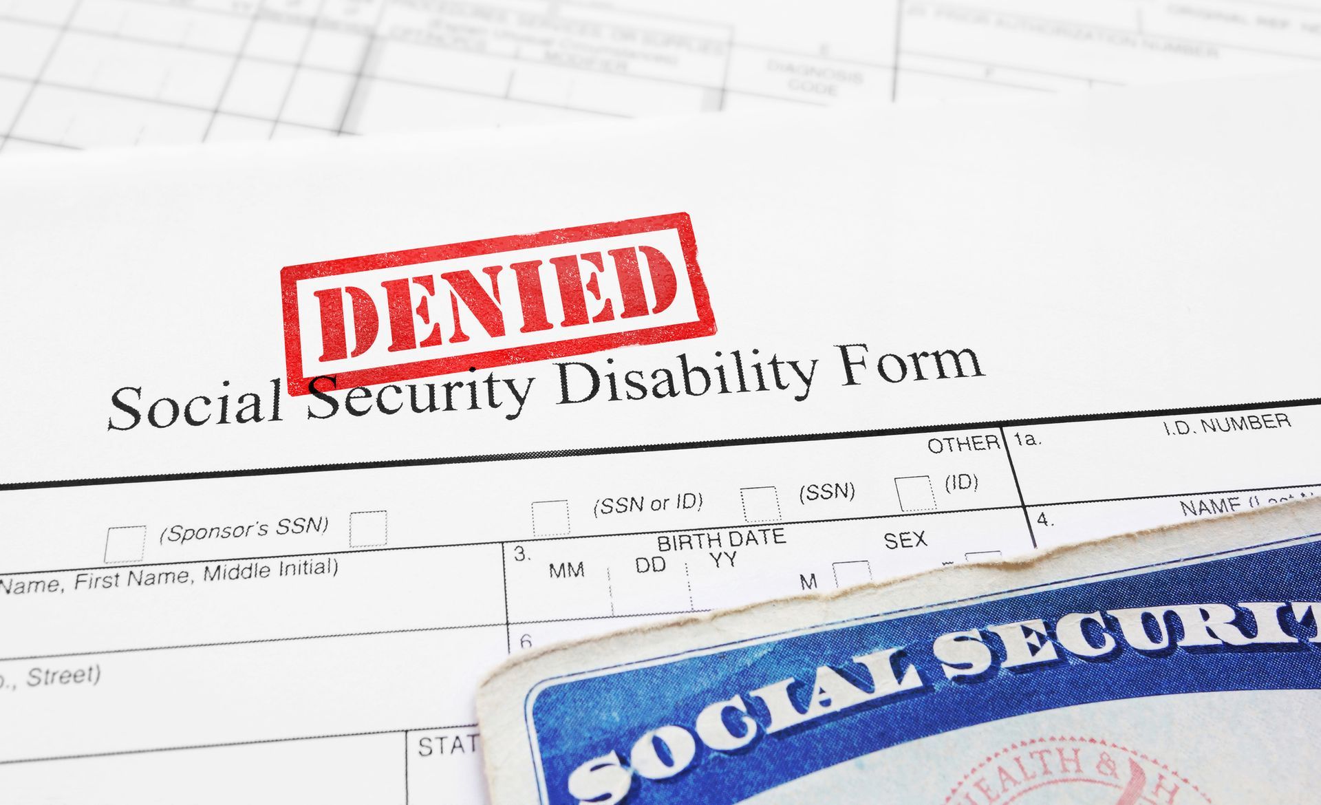 A denied social security disability form next to a social security card