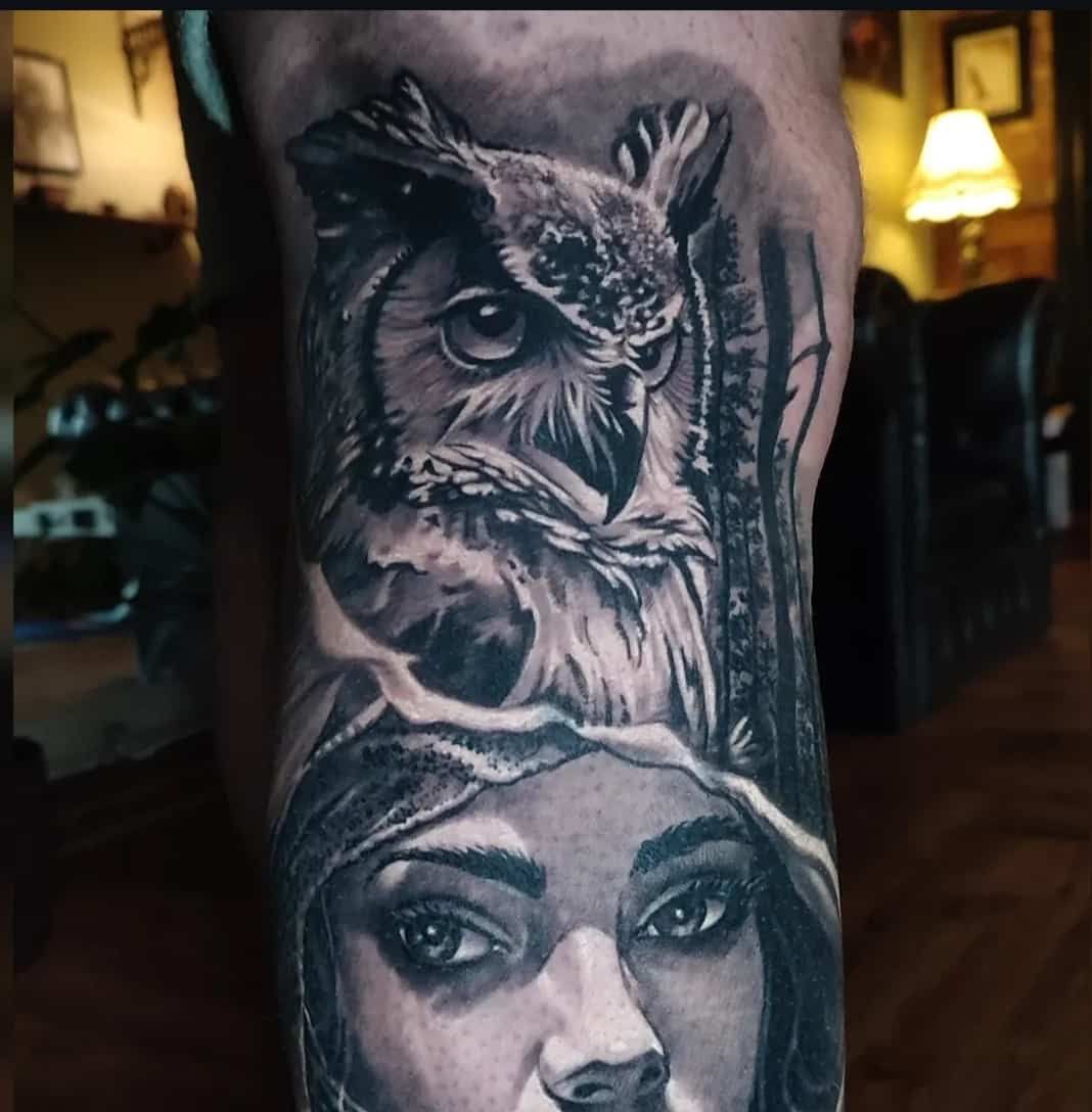Tattoo of an owl above a woman's face, detailed black and white shading on arm.