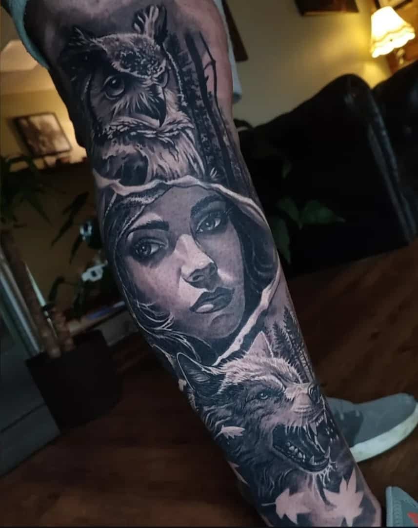 Tattoo sleeve featuring an owl, woman's face, a forest, and a wolf; all in grayscale.