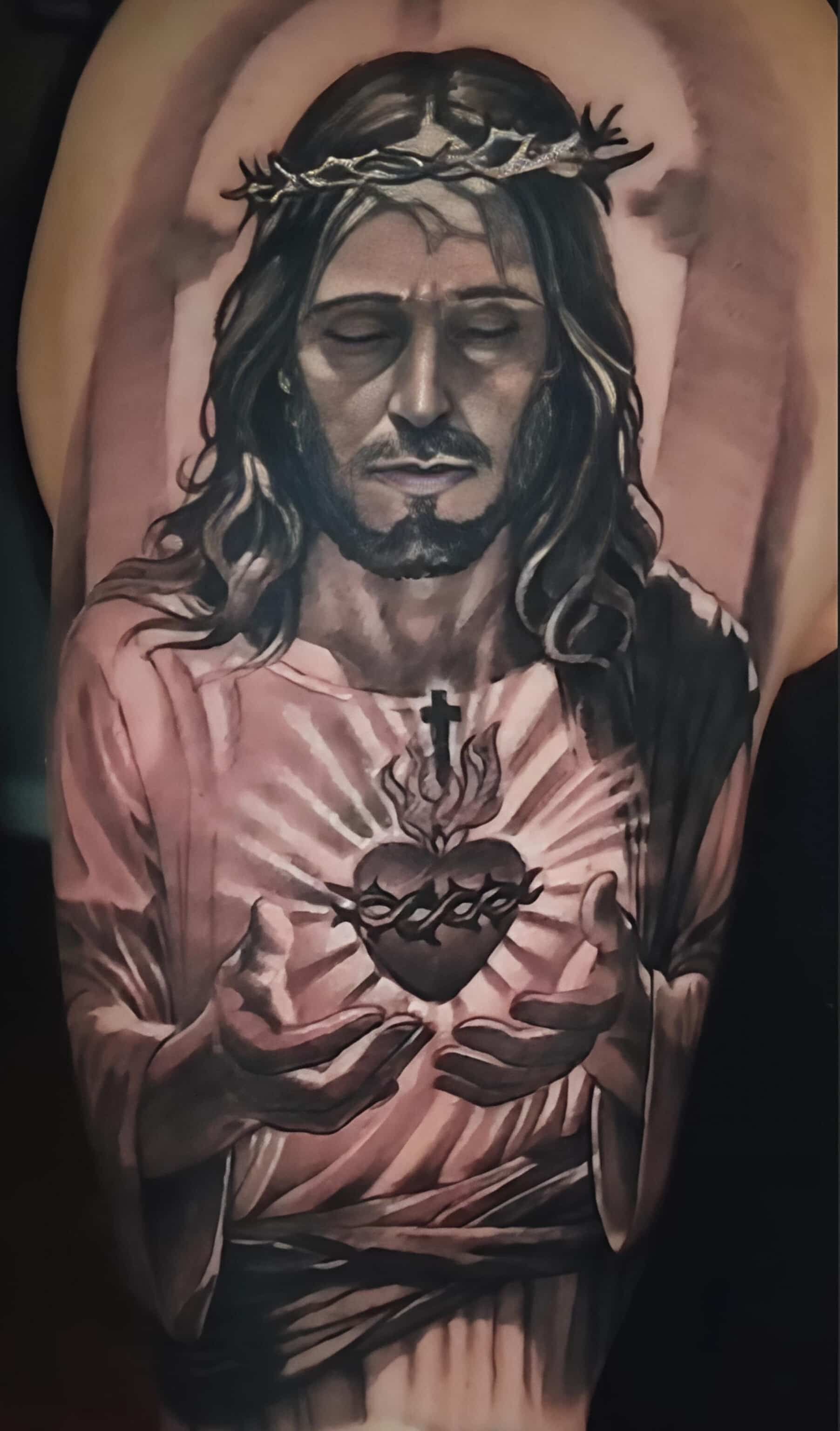 Jesus with a crown of thorns, holding a flaming heart; grayscale tattoo.