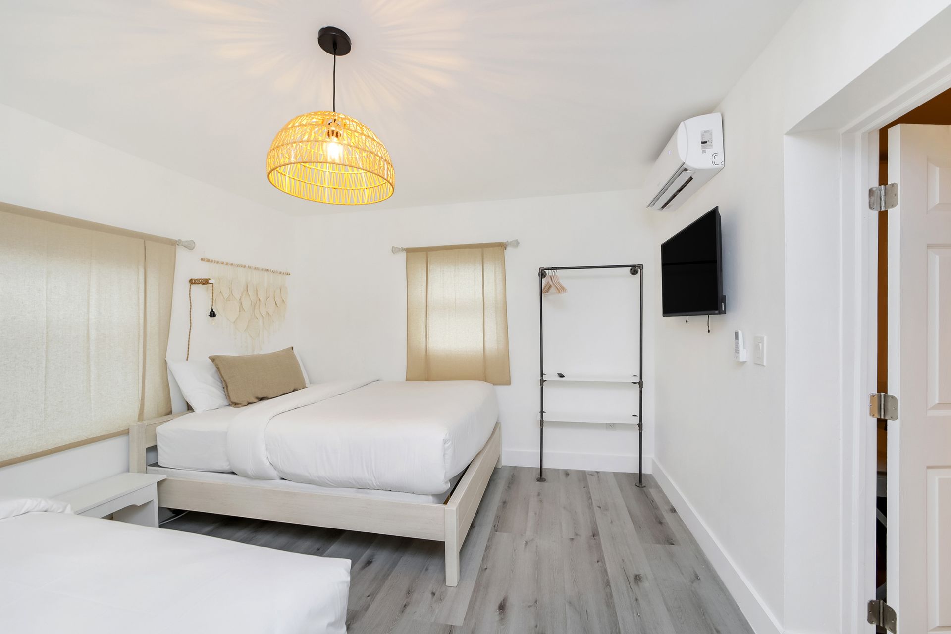Bedroom with two twin beds, a hanging lamp, and a mounted TV.