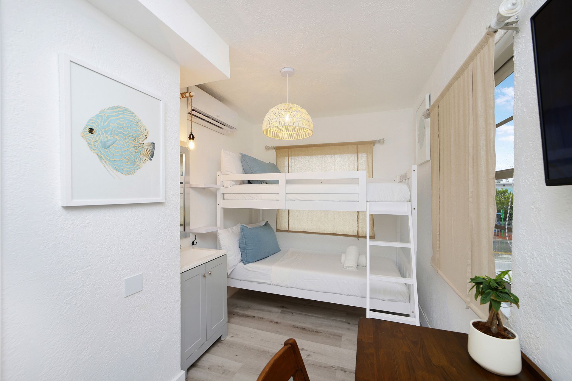 Small white bedroom with bunk beds, art, and a small desk.
