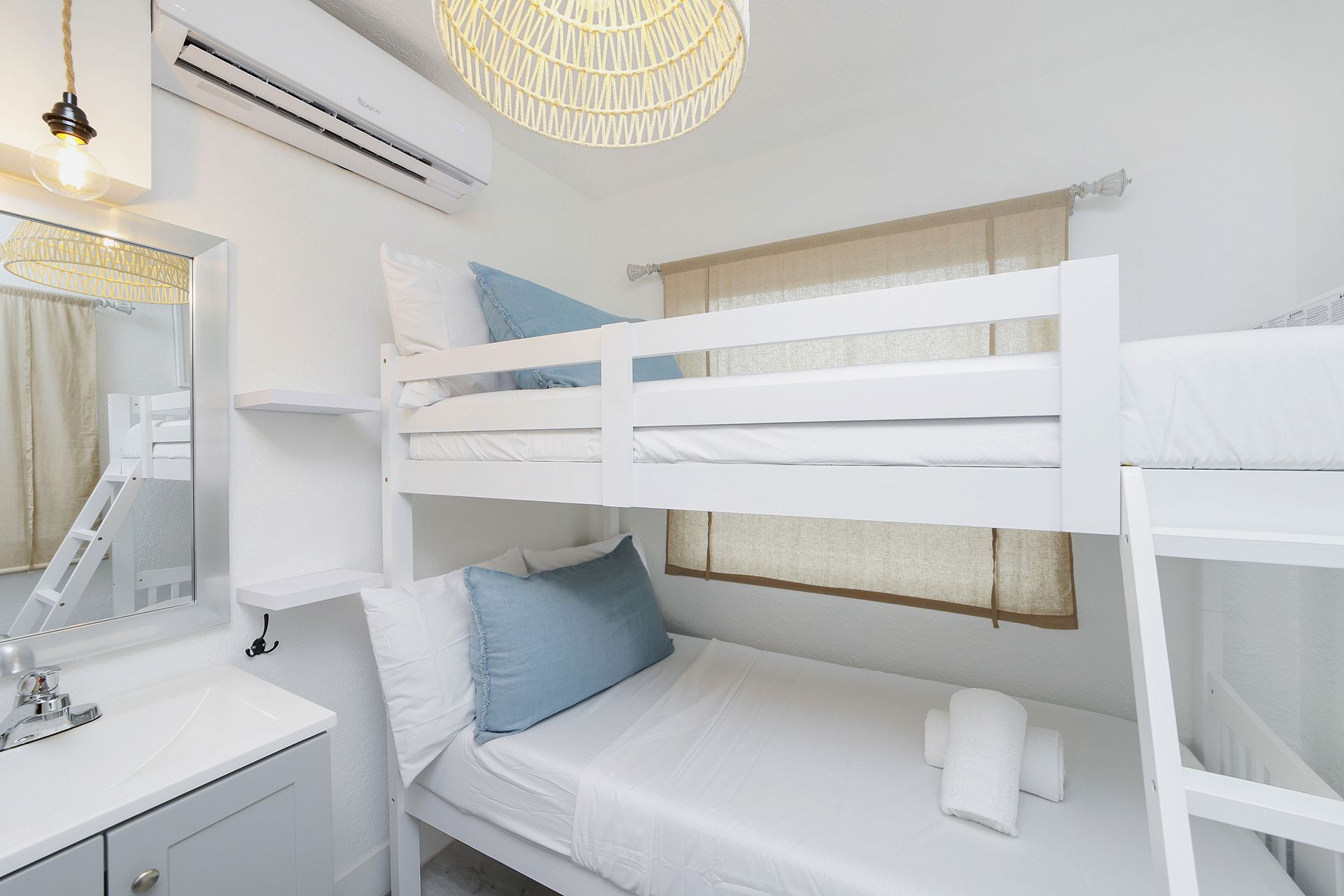 A small bedroom with a white bunk bed, a window, and a white sink.