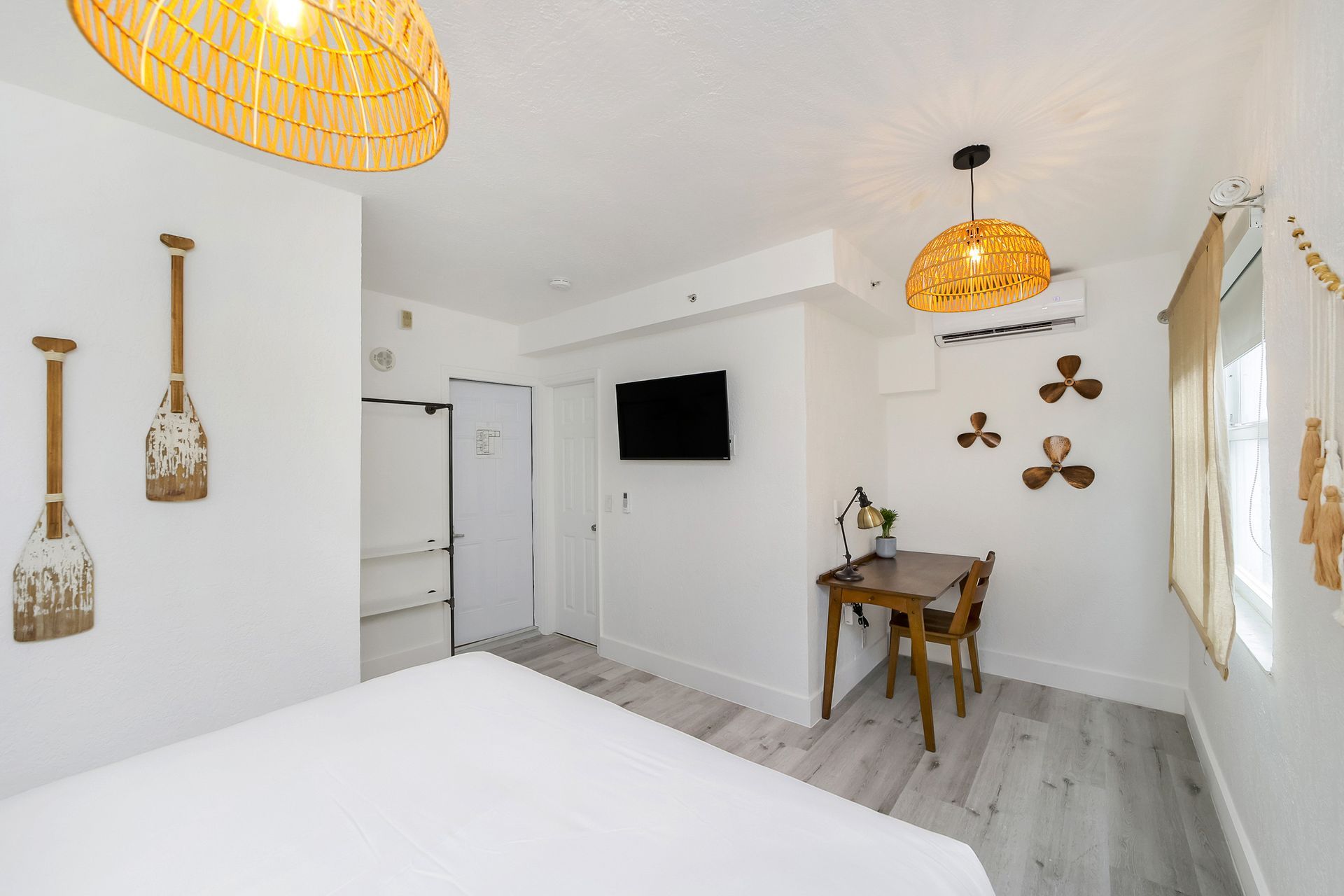 White bedroom with wooden decor, bed, table, and TV.