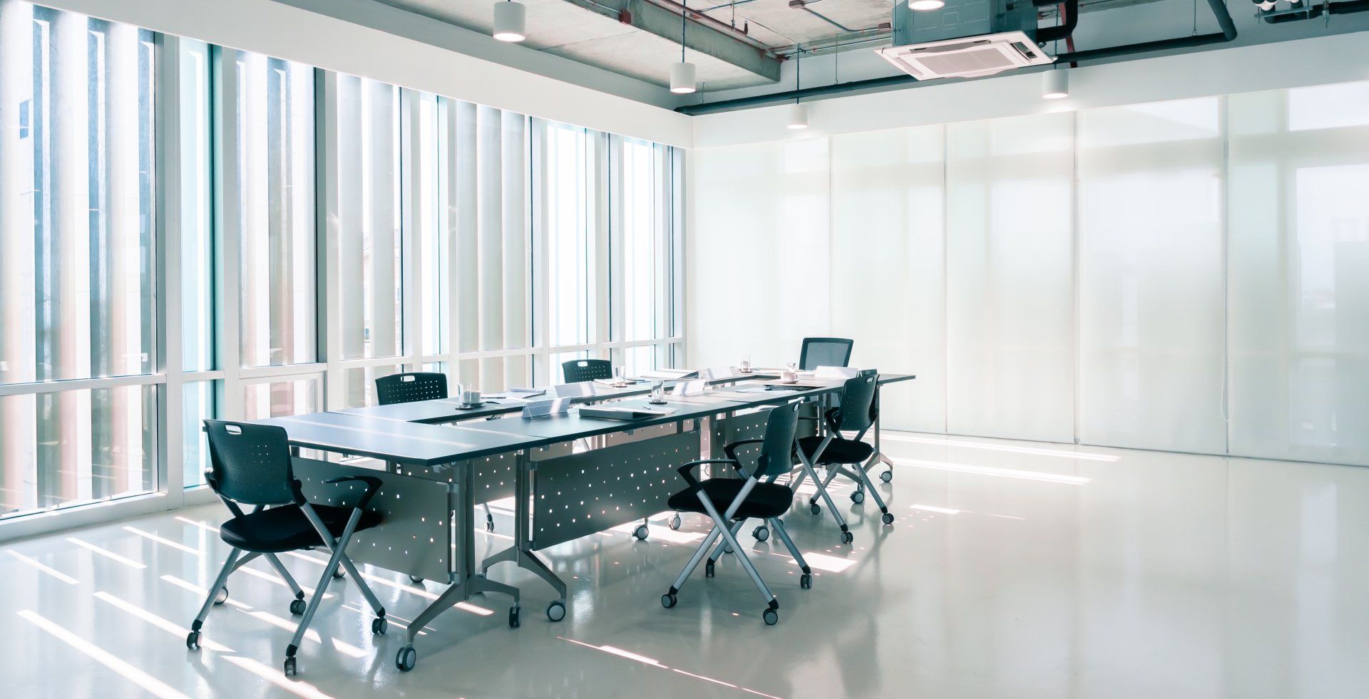 An empty conference room with a long table and chairs.