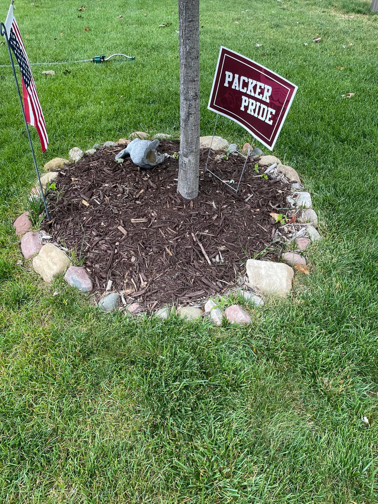 A snow-covered agricultural field with rows of dormant crop stubble extending toward a distant treeline under a blue sky.