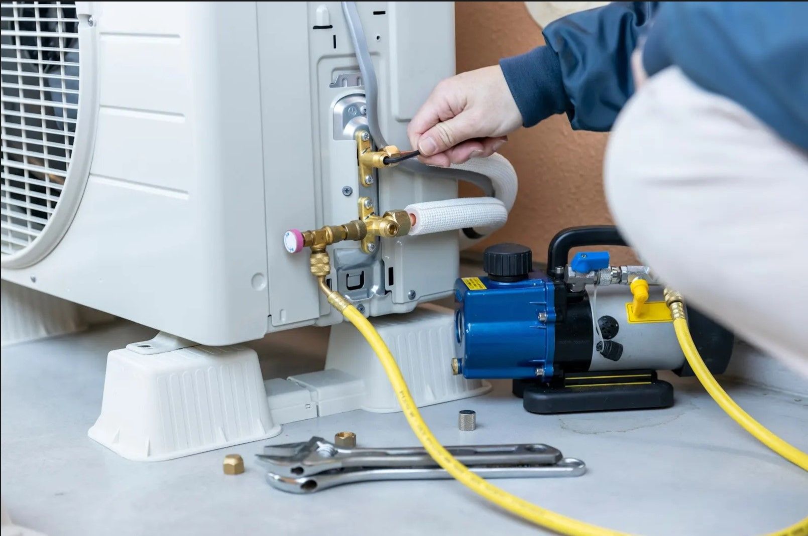 A person is working on an air conditioner with a vacuum pump.