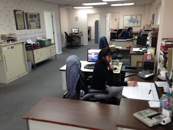 A woman sits at a desk in an office talking on a cell phone