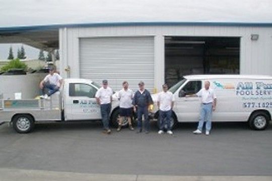 A group of men standing in front of a pool service van