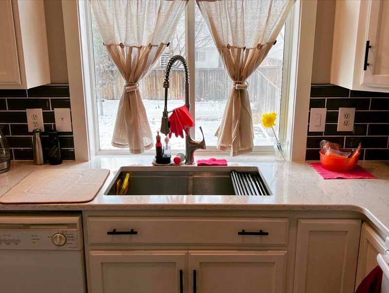 A kitchen with a sink and a window with curtains