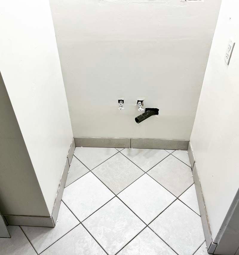 A corner of a room with a tiled floor and a white wall