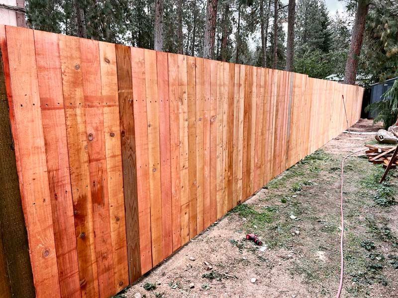 A long wooden fence is sitting in the middle of a yard.