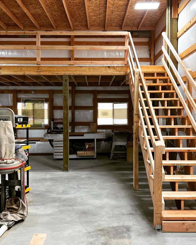 A wooden staircase leading up to a loft in a garage.