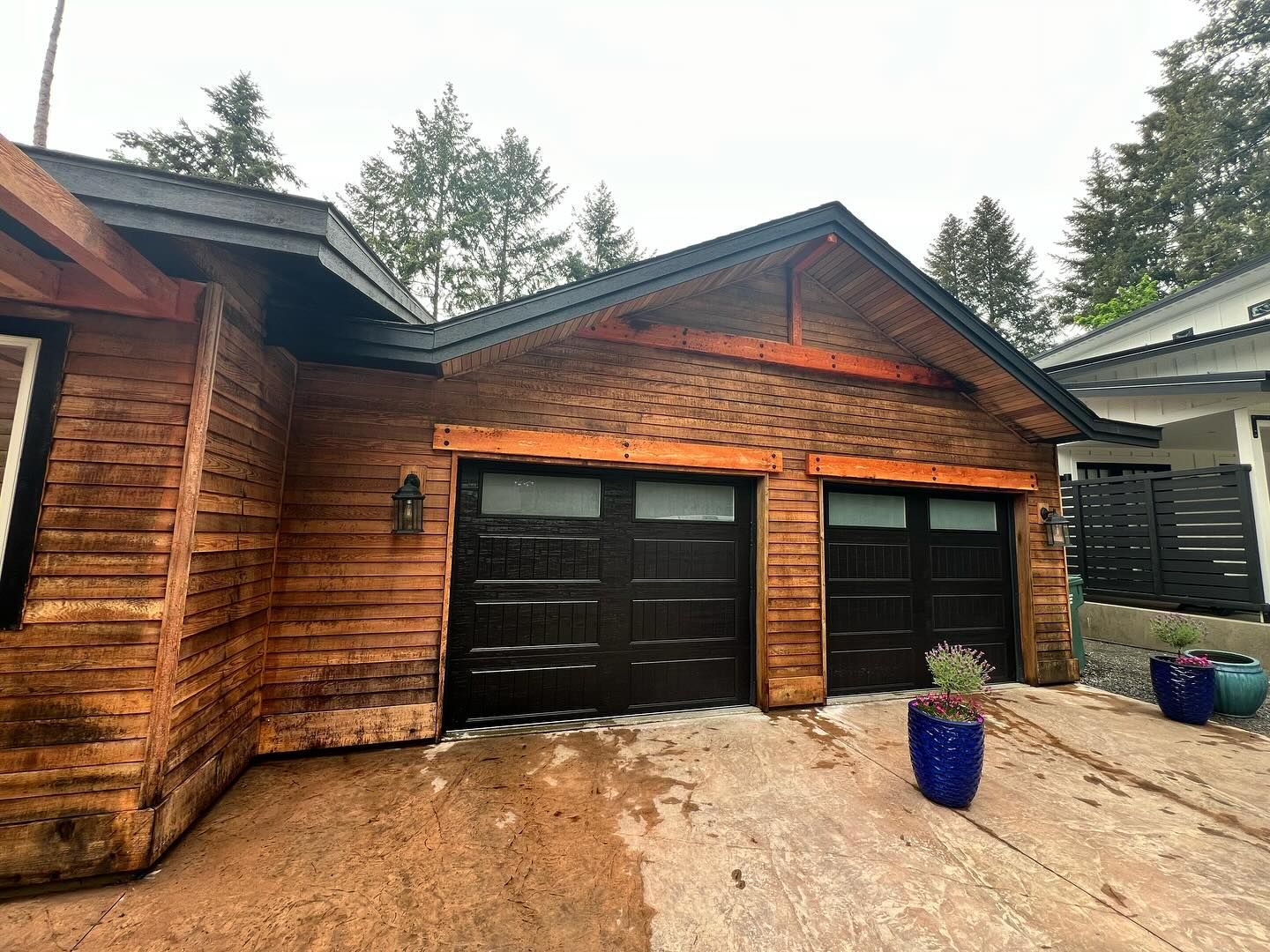 A house with a garage and potted plants in front of it.