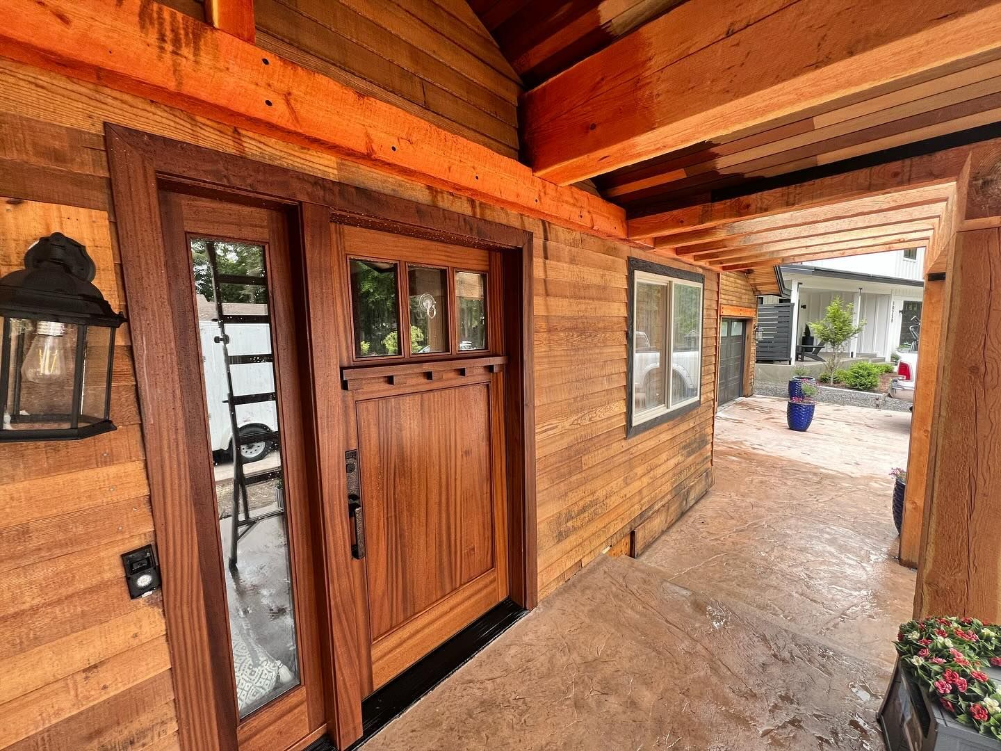 A wooden house with a large wooden door and windows.