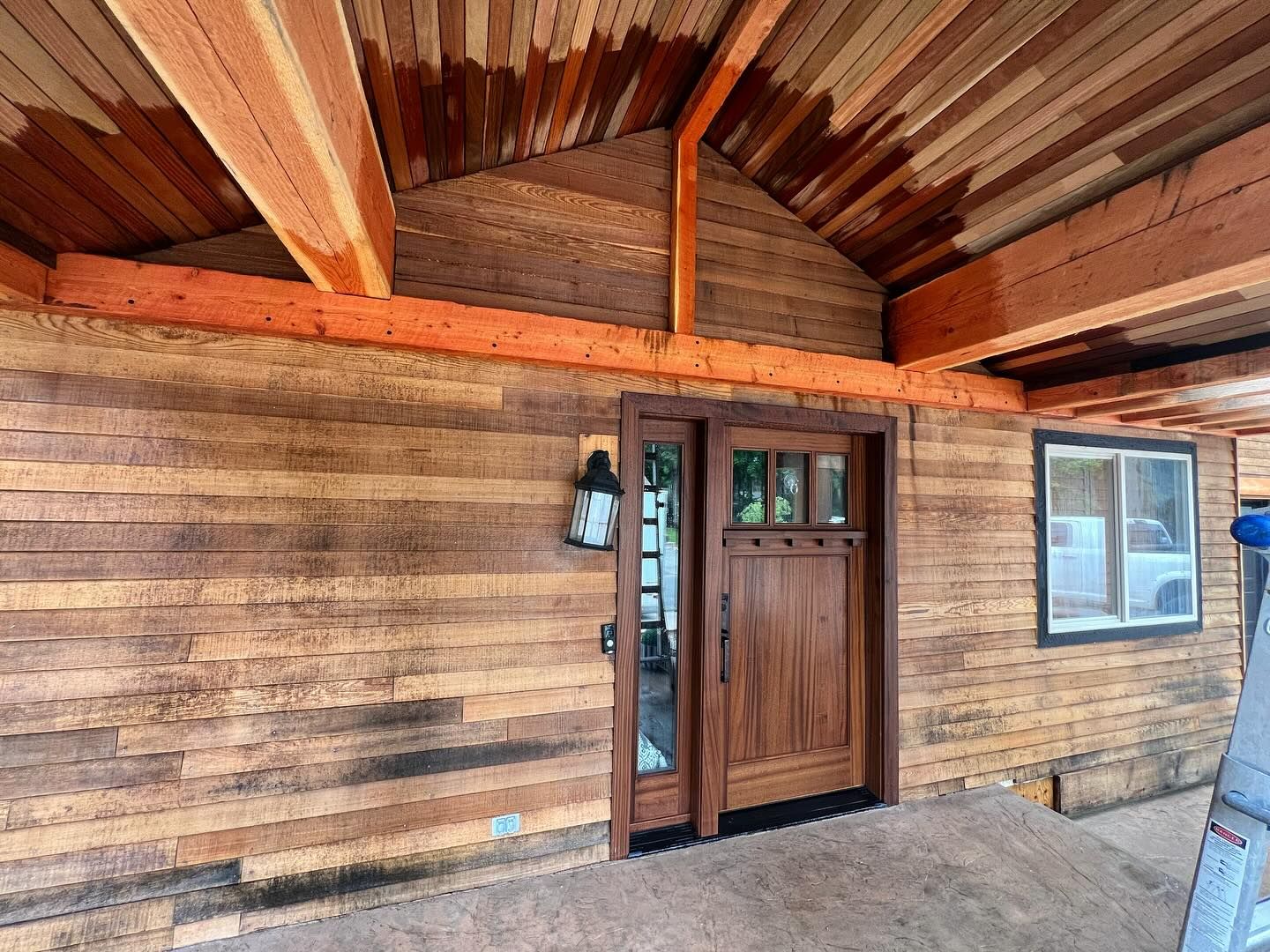 A wooden house with a wooden door and a ladder in front of it.