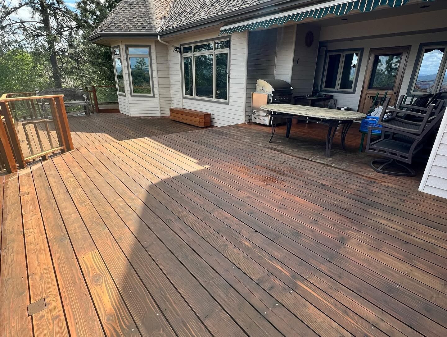A large wooden deck with a table and chairs on it in front of a house.