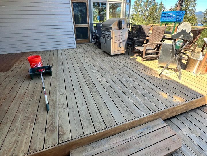 A wooden deck with a grill and chairs on it.