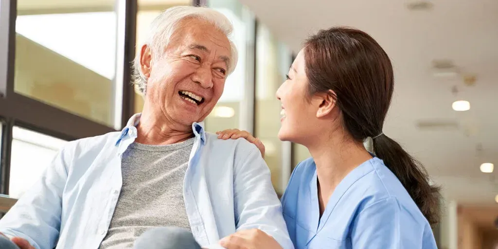 A nurse is talking to an elderly man in a wheelchair.