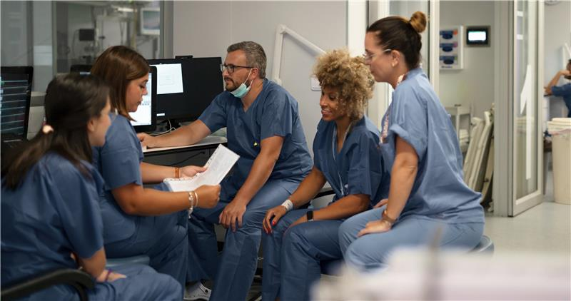 Group of 5 international nurses sitting together near computer
