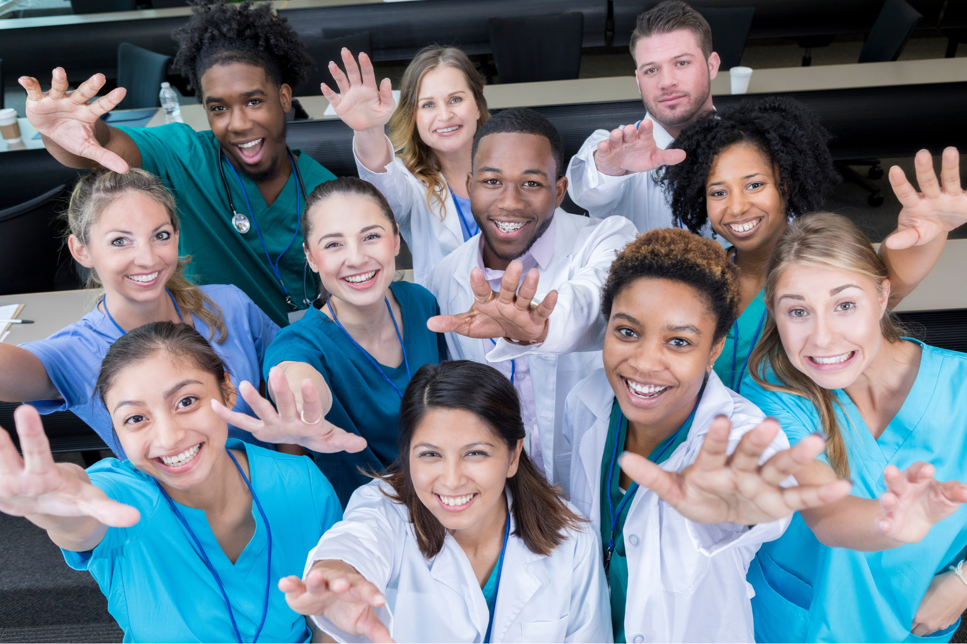 A group of doctors and nurses are posing for a picture in a classroom.
