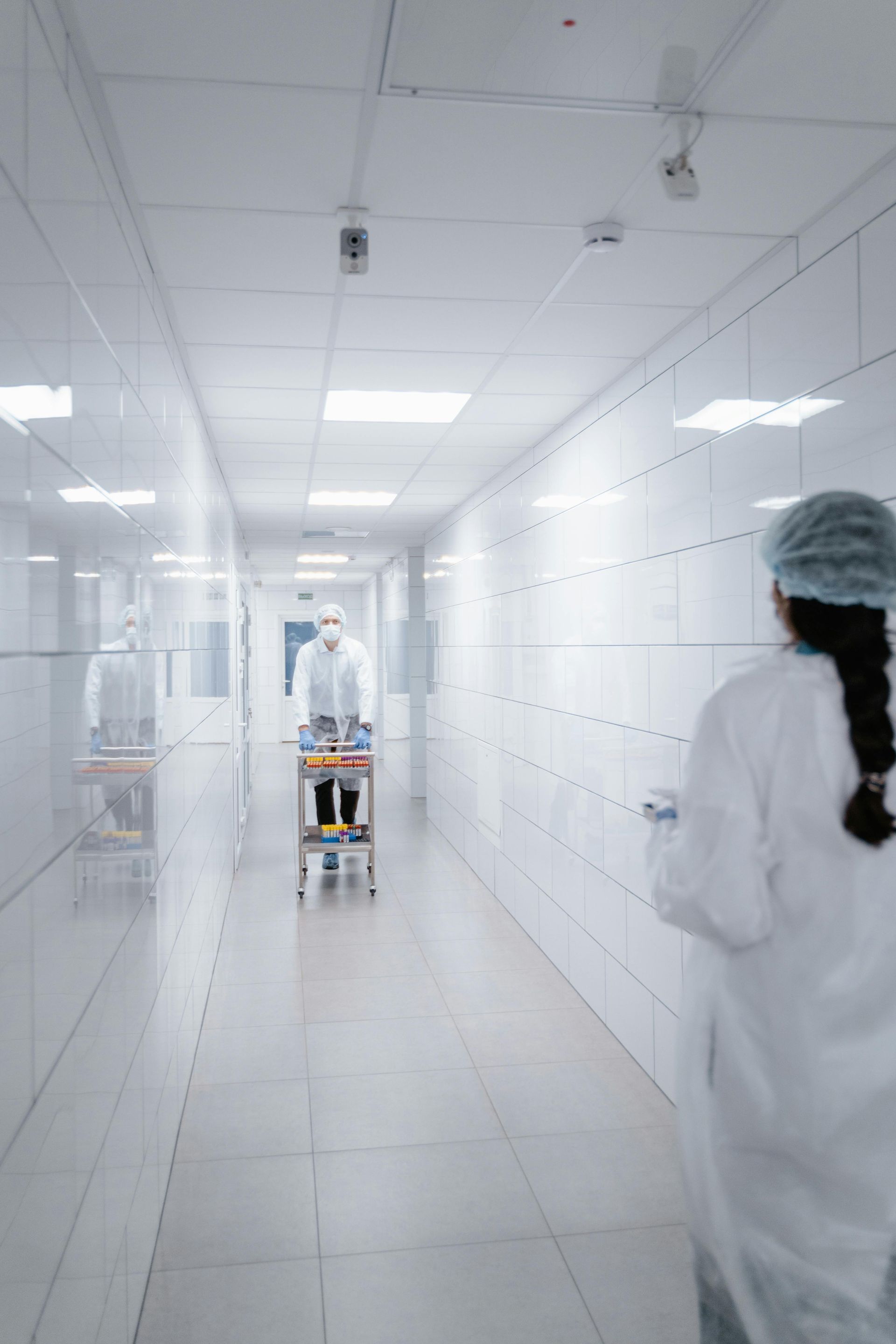 A woman in a lab coat is walking down a hospital hallway.