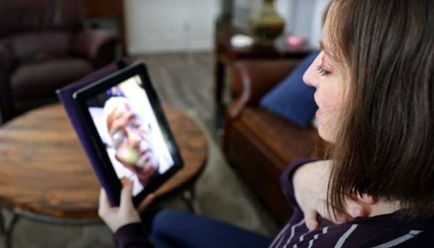 A woman is sitting in a chair looking at a tablet.